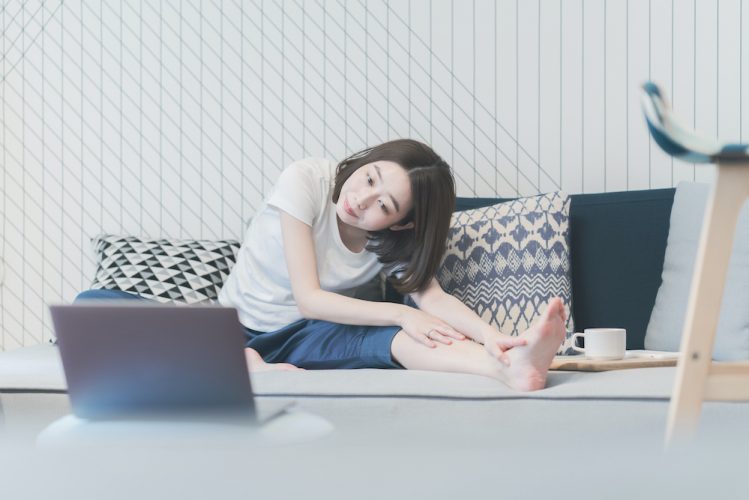 Young Asian woman taking an online yoga lesson in the living room